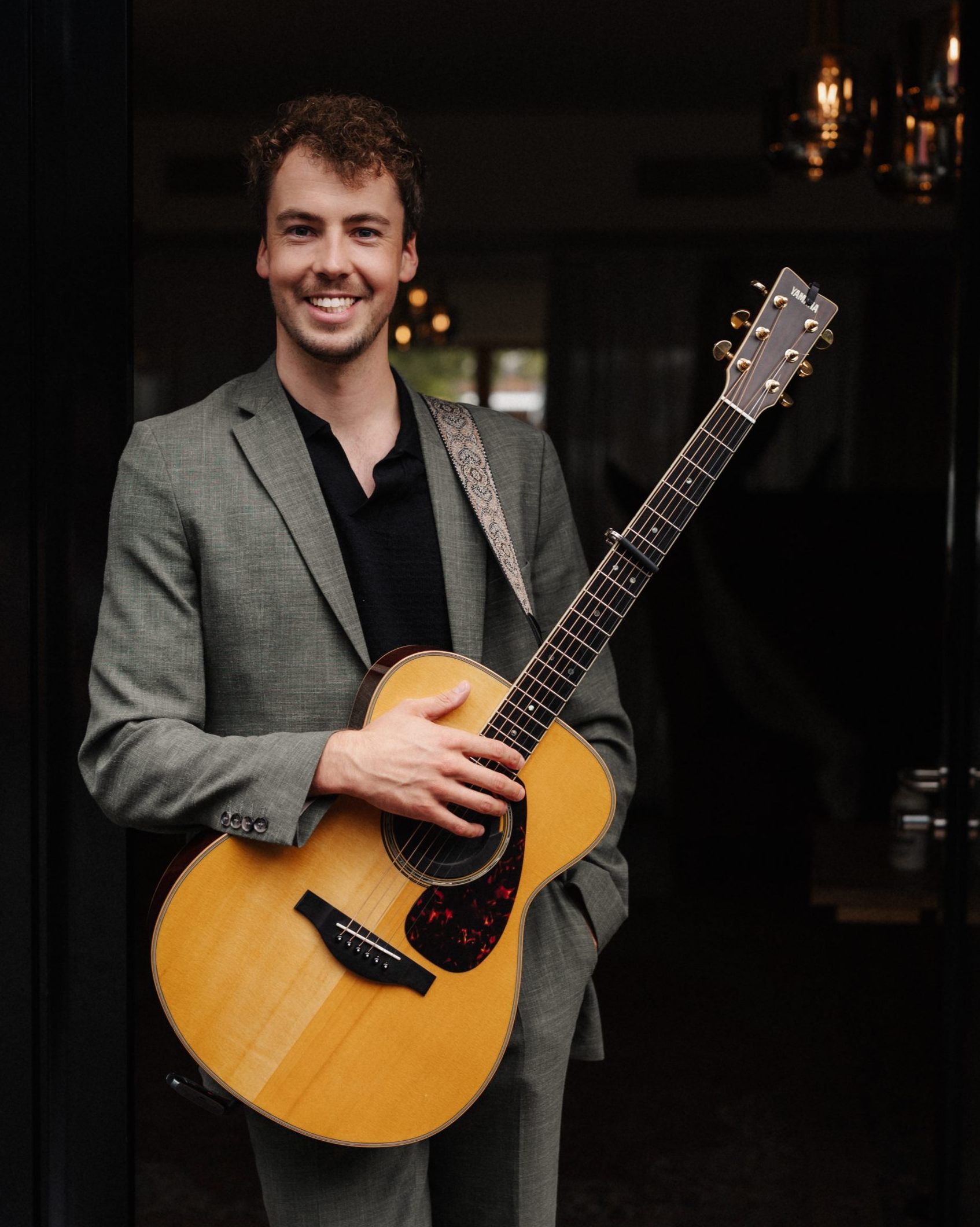 Hochzeitssänger Elias Tebroke lächelnd mit Gitarre