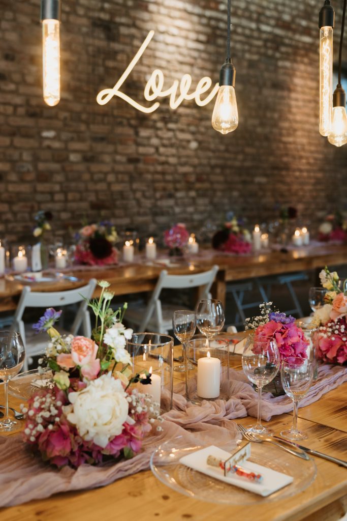 Mit Blumen geschmückter langer Tisch, der für das Hochzeitsessen bereitsteht